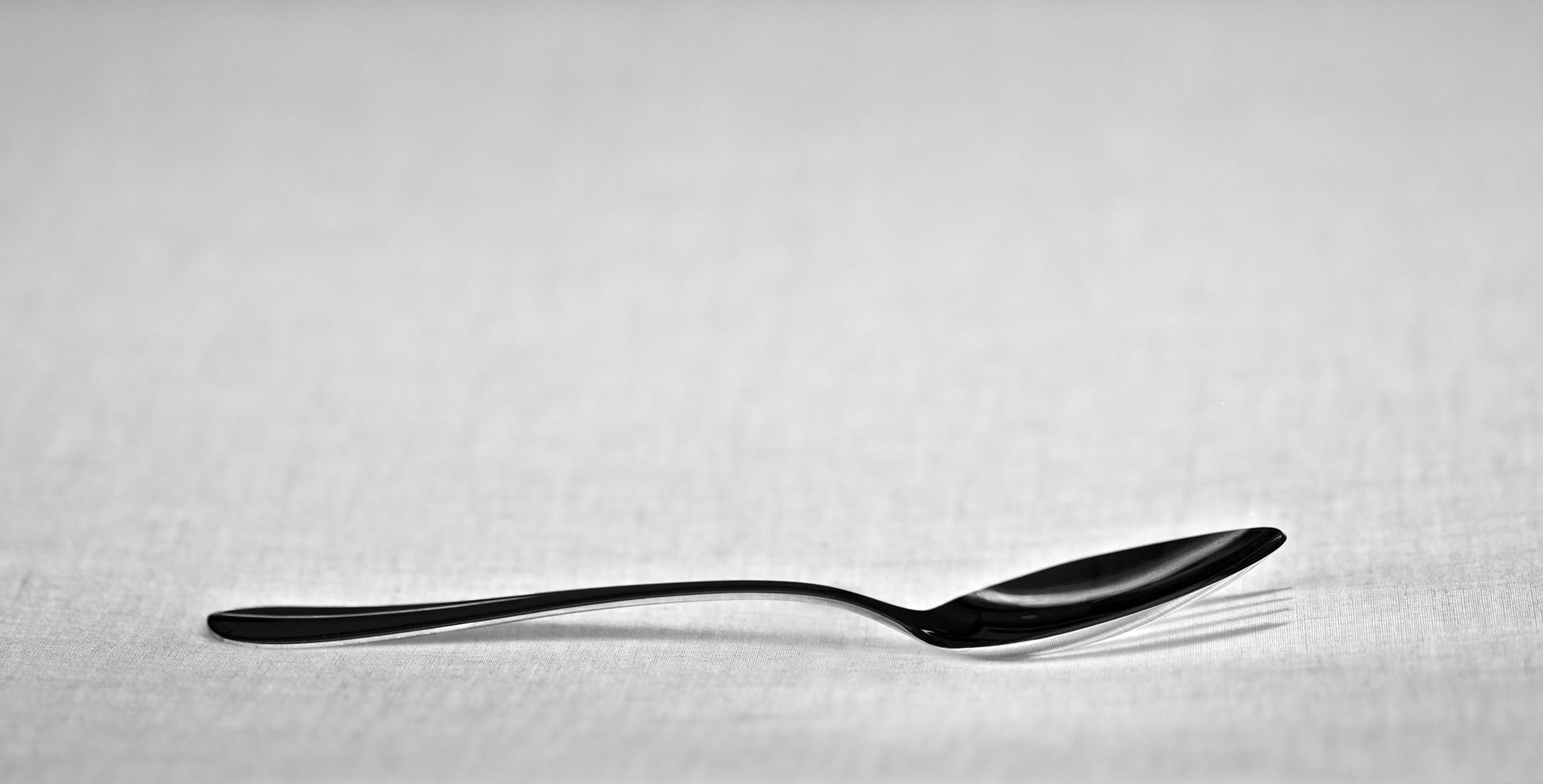 A spoon with the shadow of a fork