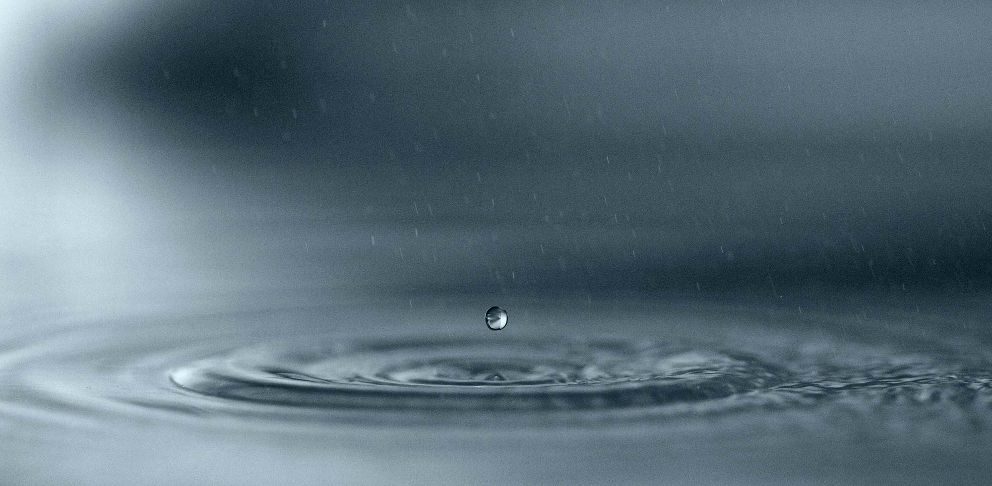 A drop of water suspended in air above its ripples